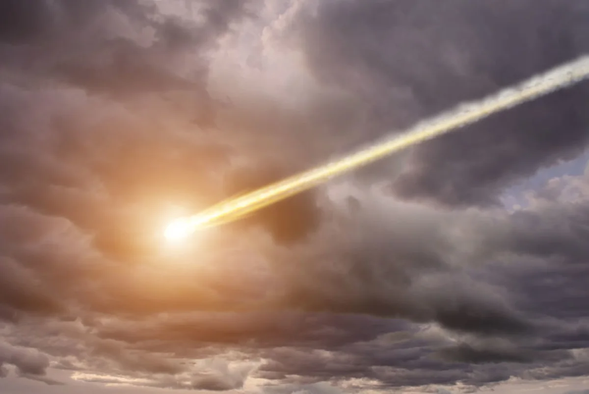 Bright meteor-like streak crossing dark storm clouds, glowing intensely near the lower-left portion of the sky.