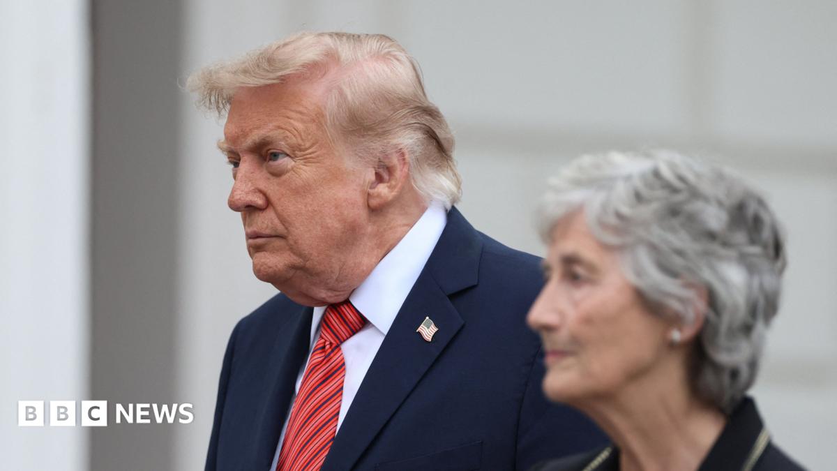 Donald Trump walks beside an older gray-haired woman in a formal indoor setting.