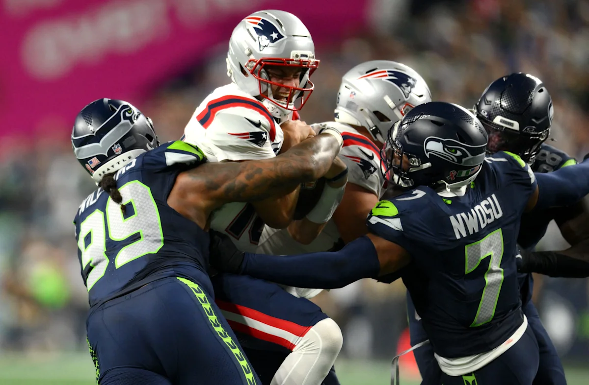 Patriots quarterback surrounded by Seahawks defenders during a tense football play