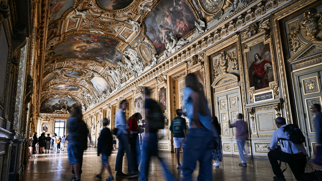 Visitors move through an ornate museum gallery lined with framed paintings and elaborate gilded decorations.