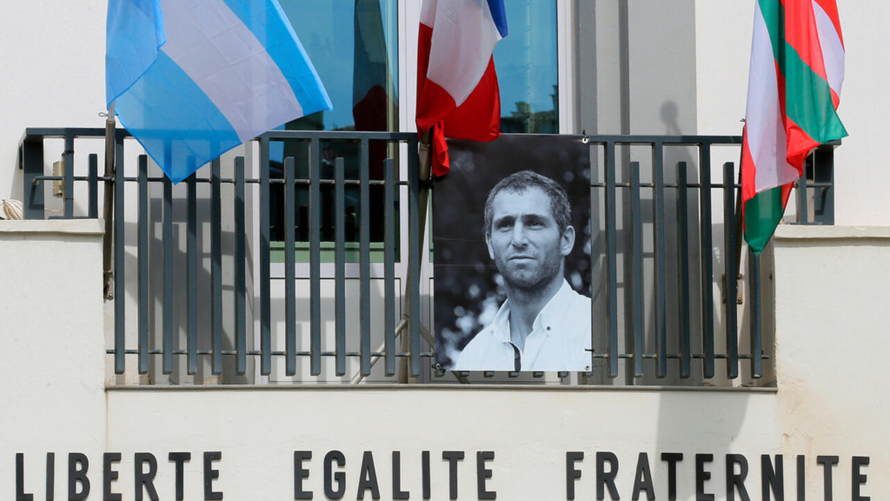 Flags hang above a black-and-white portrait displayed on a building facade.
