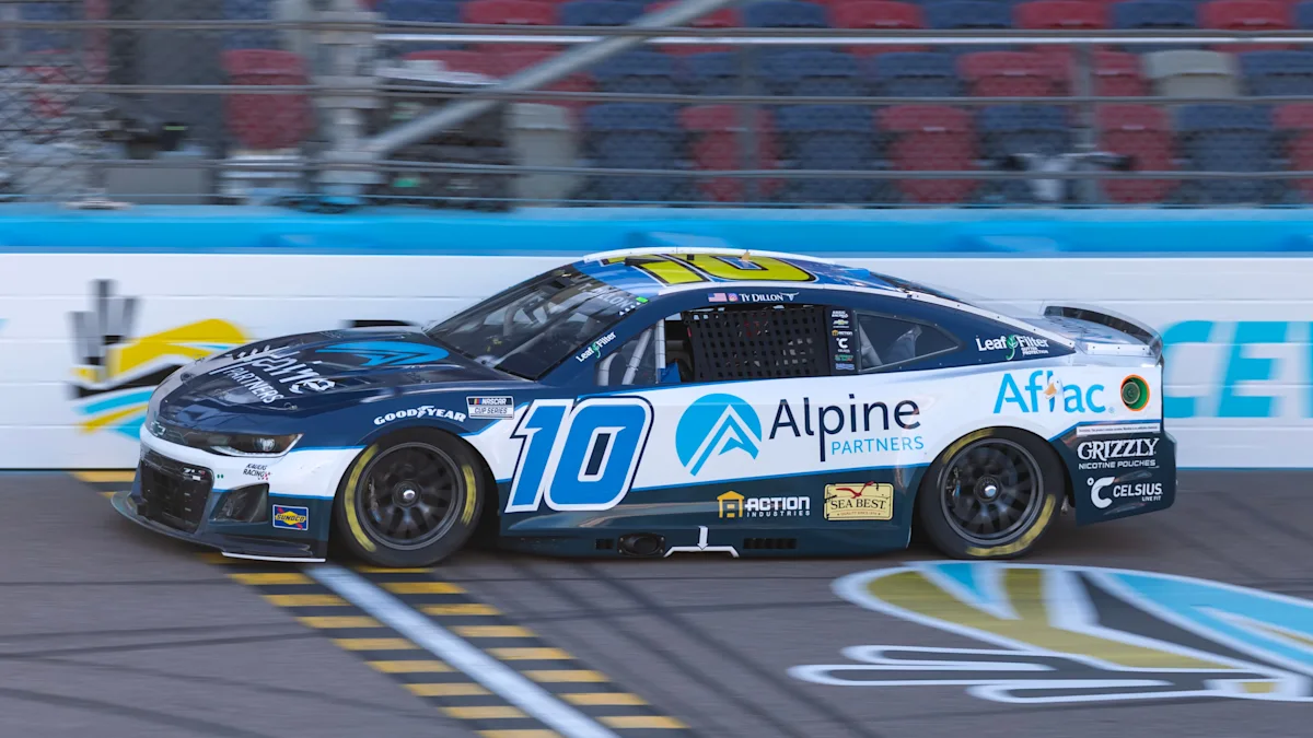 Blue and white No. 10 Alpine-sponsored stock car speeds along a racetrack past empty grandstand seats.