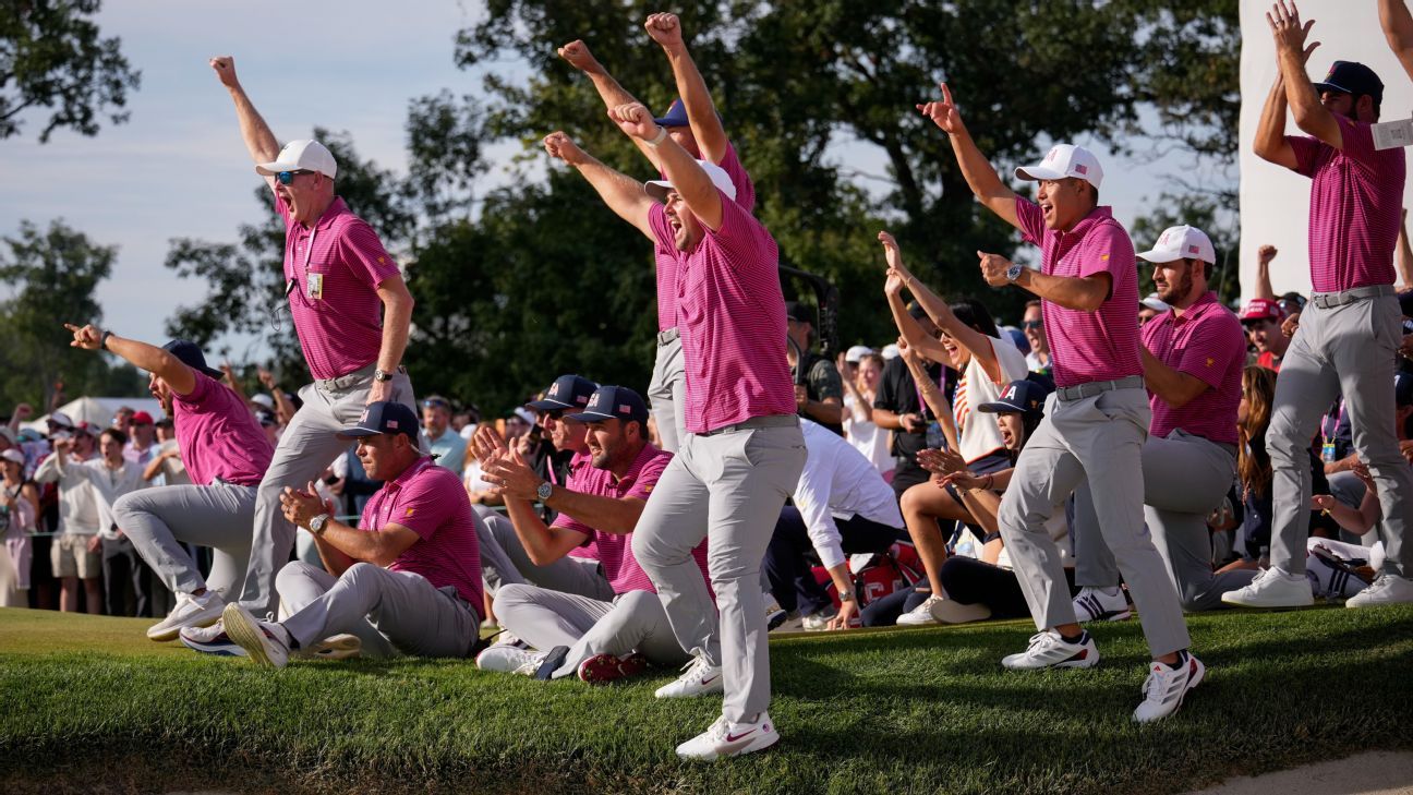 Golfers in magenta shirts celebrate beside a crowd, raising fists and applauding on a grassy course.