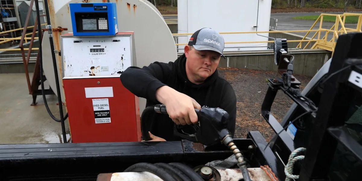 Worker in a Scania cap refuels a vehicle with diesel at an industrial fueling station.