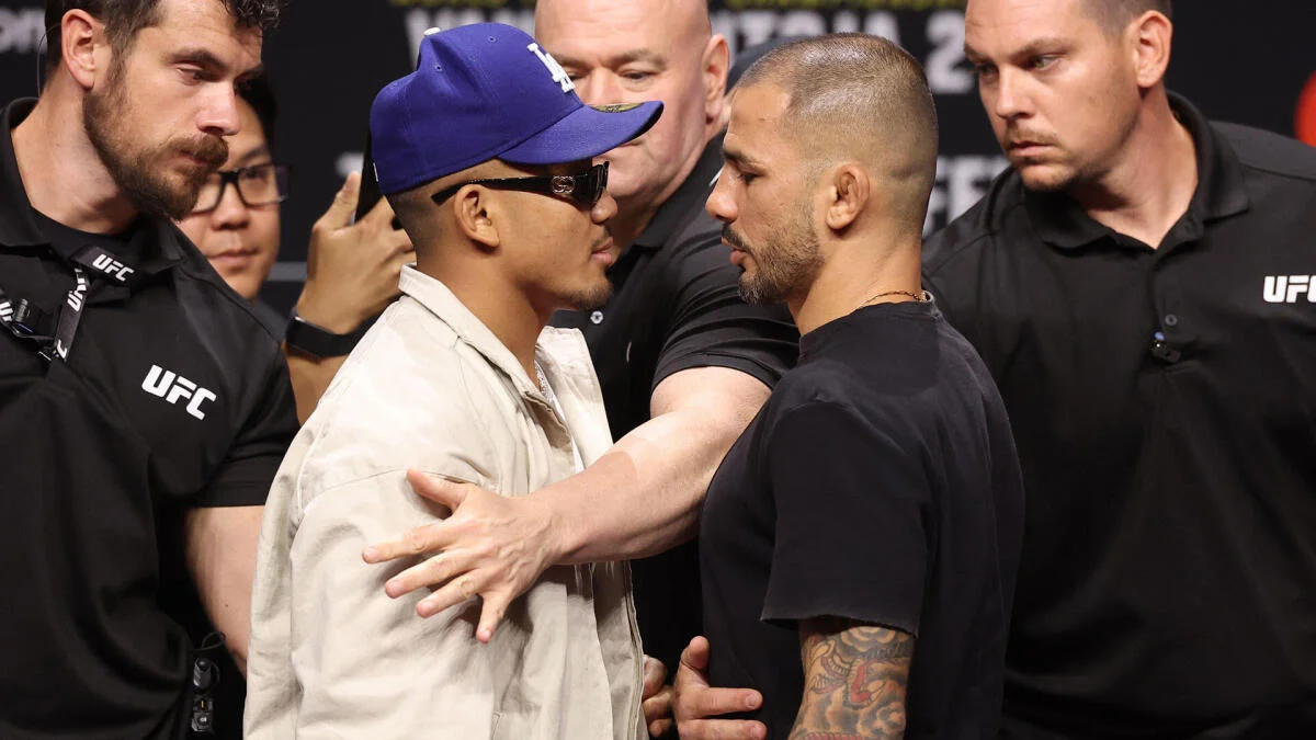 Two UFC fighters face each other closely as officials separate them during a tense staredown.