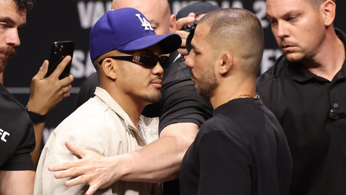 Two men face off closely as security personnel separate them at a UFC event.