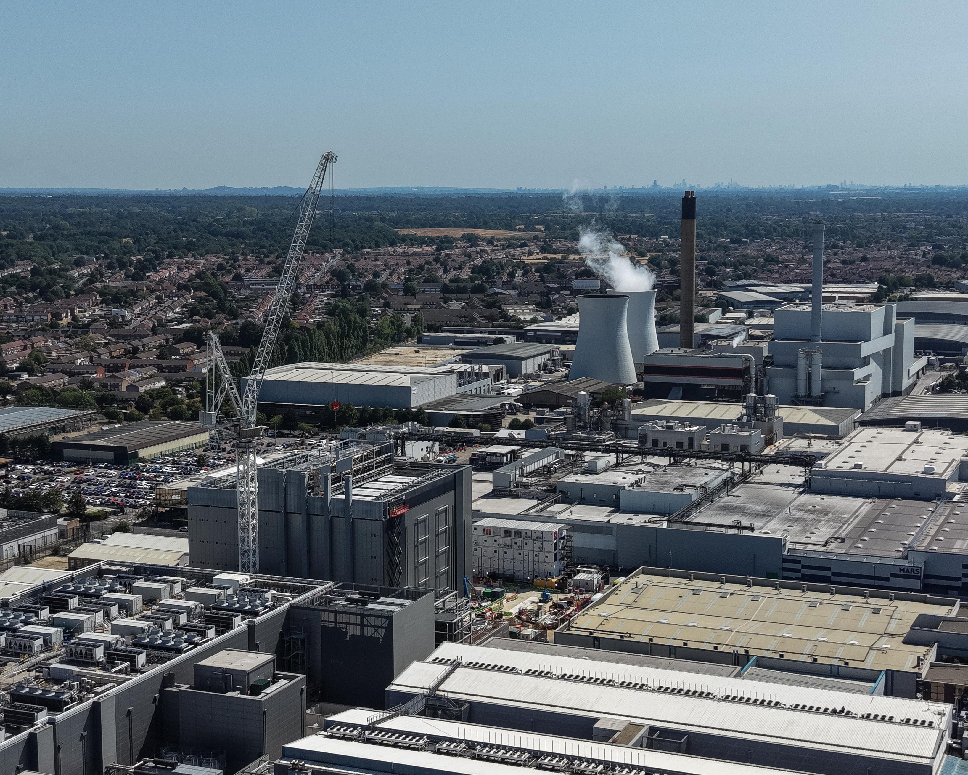 Aerial view of an industrial facility with cooling towers, smokestacks, warehouses and nearby residential buildings.