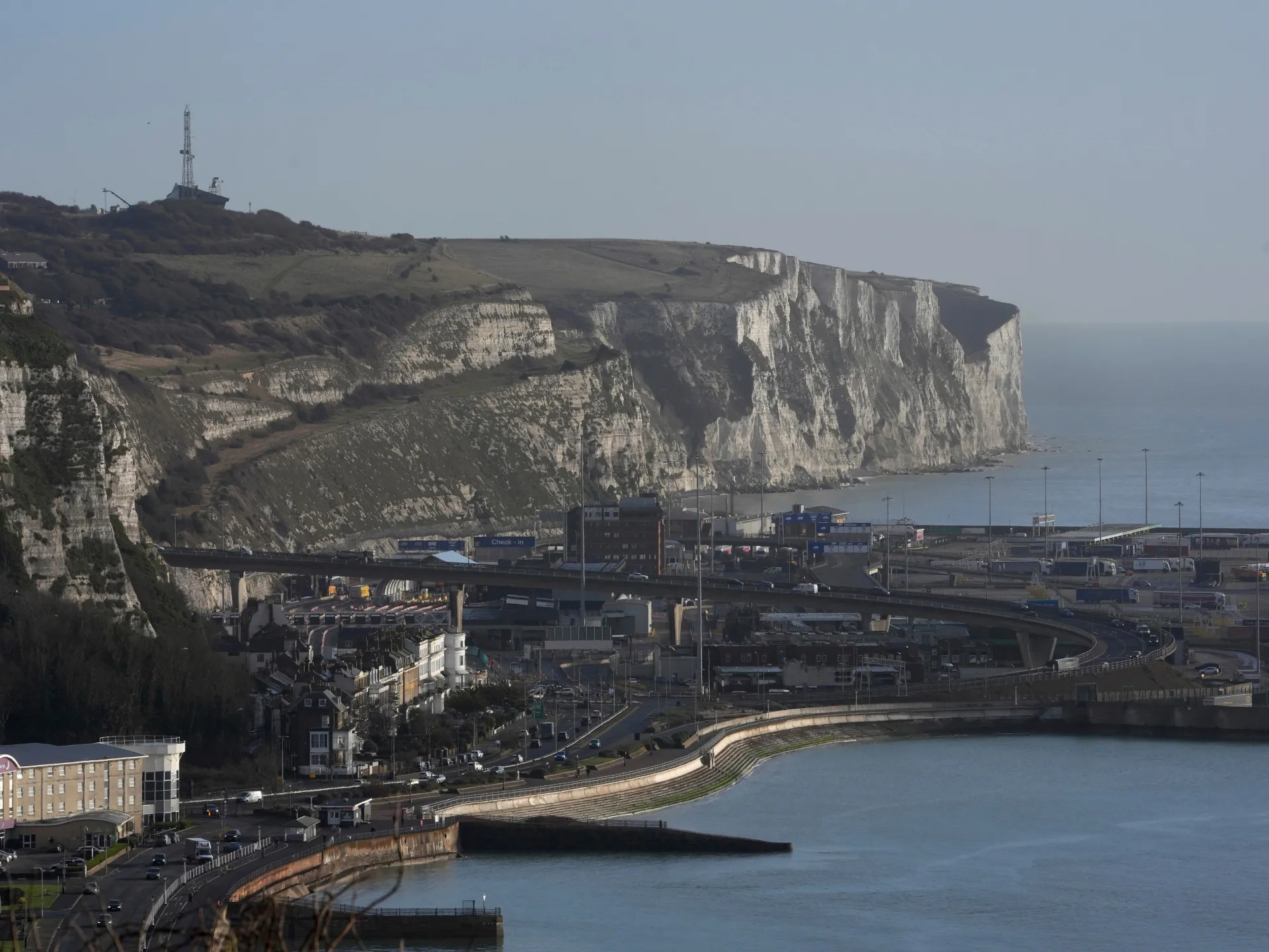 White chalk cliffs overlooking a coastal ferry port, roads, buildings, and calm sea
