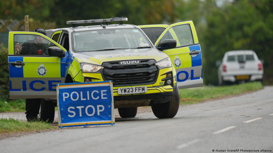 Marked police pickup with open doors beside a roadside police stop sign.