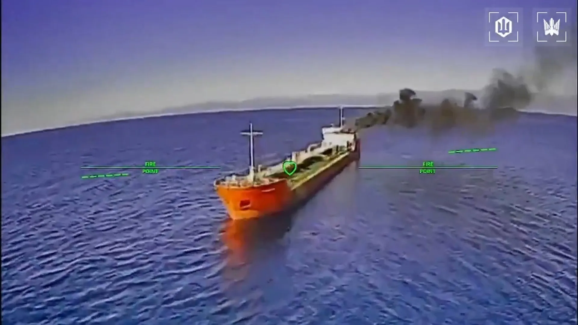 Aerial targeting view shows an orange-bowed oil tanker at sea amid smoke and fire.