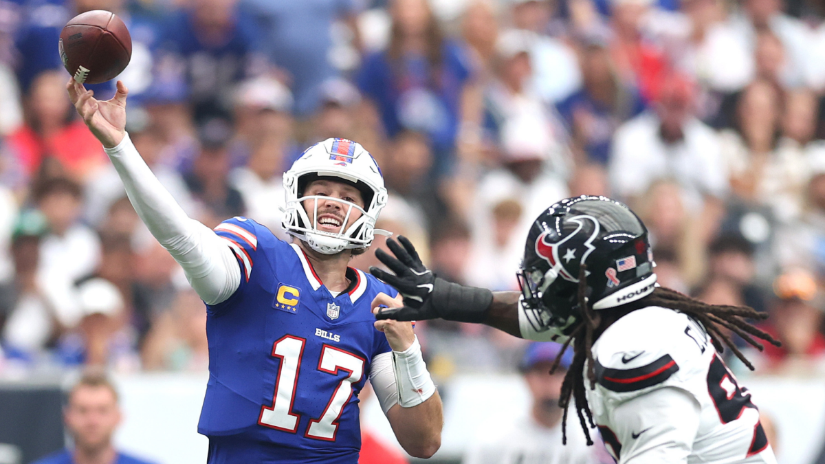 A Buffalo Bills quarterback throws a football as a Houston Texans defender closes in during play.