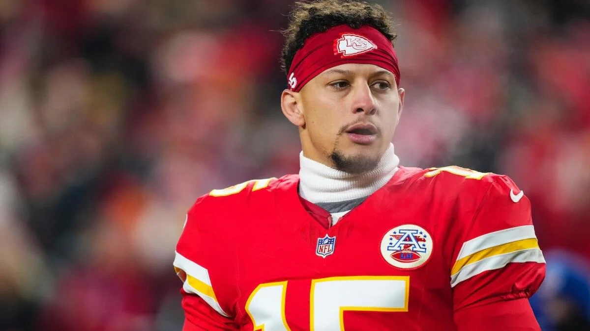 Football player in a red Kansas City jersey and headband stands on the field.
