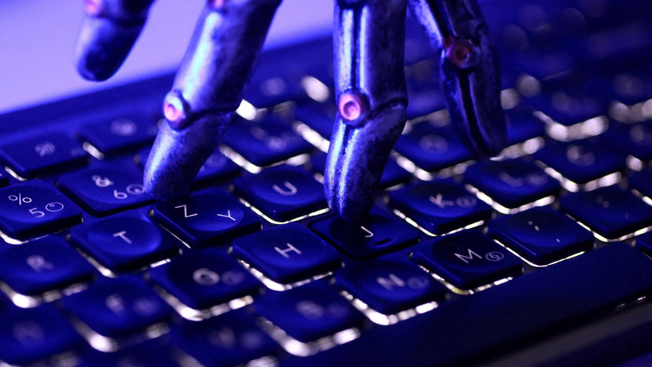 Close-up of robotic fingers pressing keys on a computer keyboard under blue-purple lighting