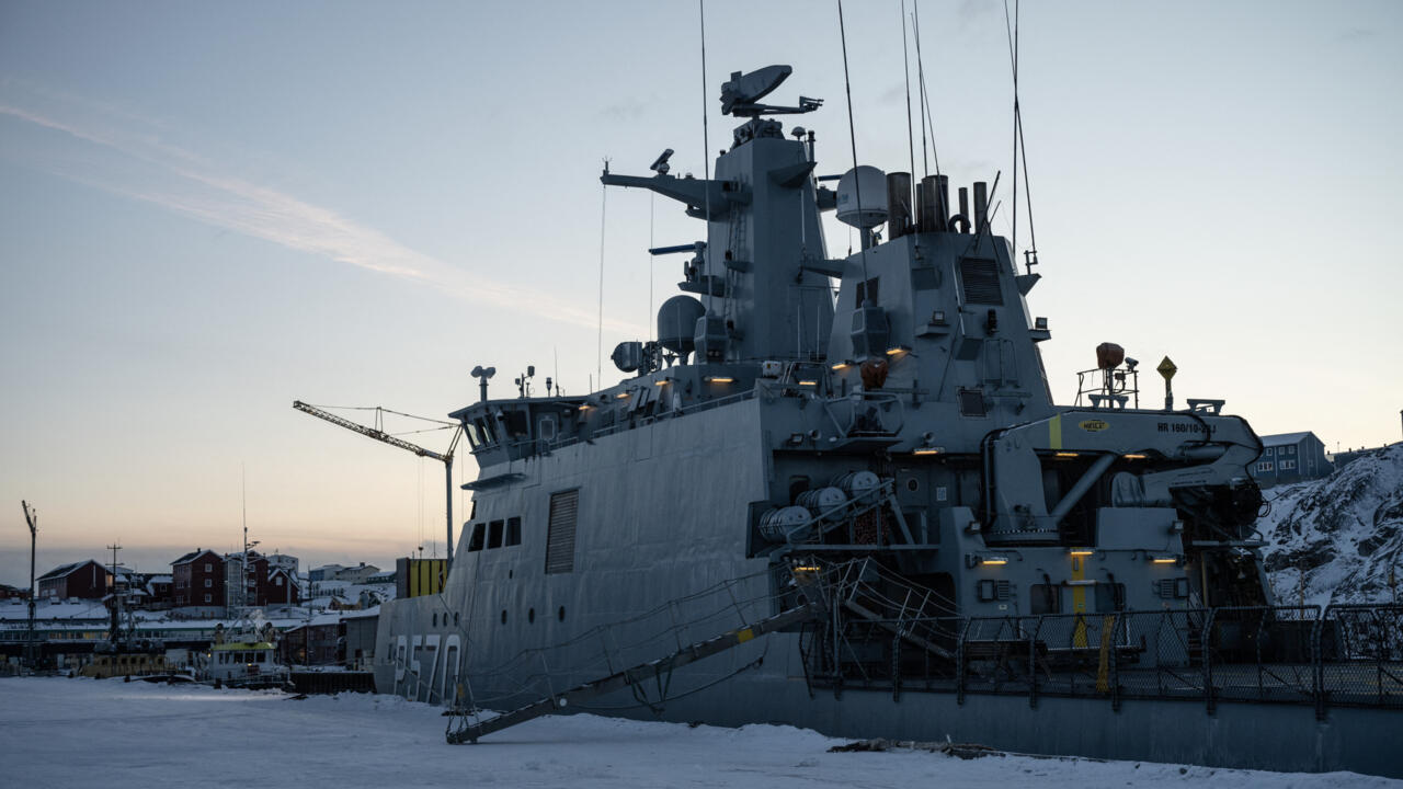 Large gray ship docked in a snowy harbor beneath a pale evening sky
