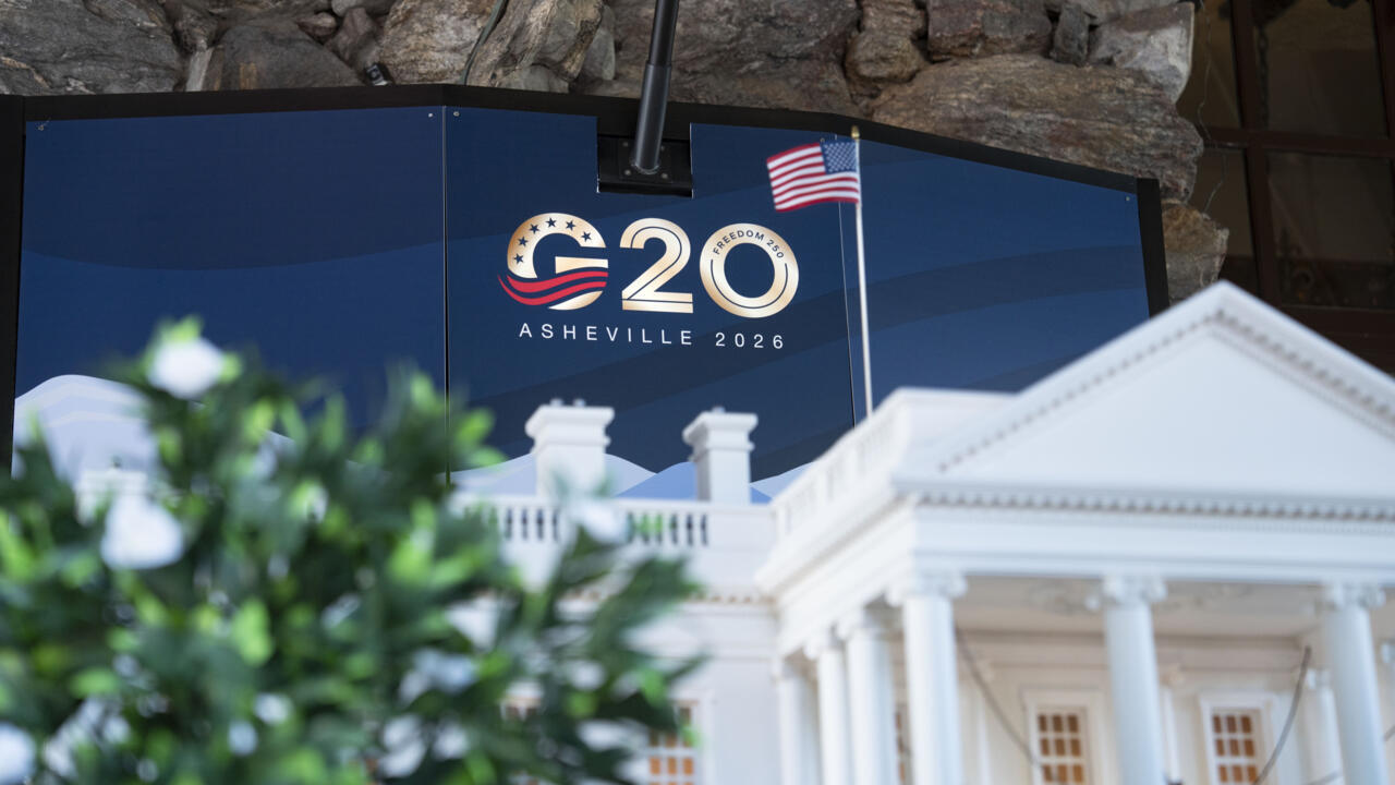 G20 2026 Asheville sign and U.S. flag behind a model of the White House