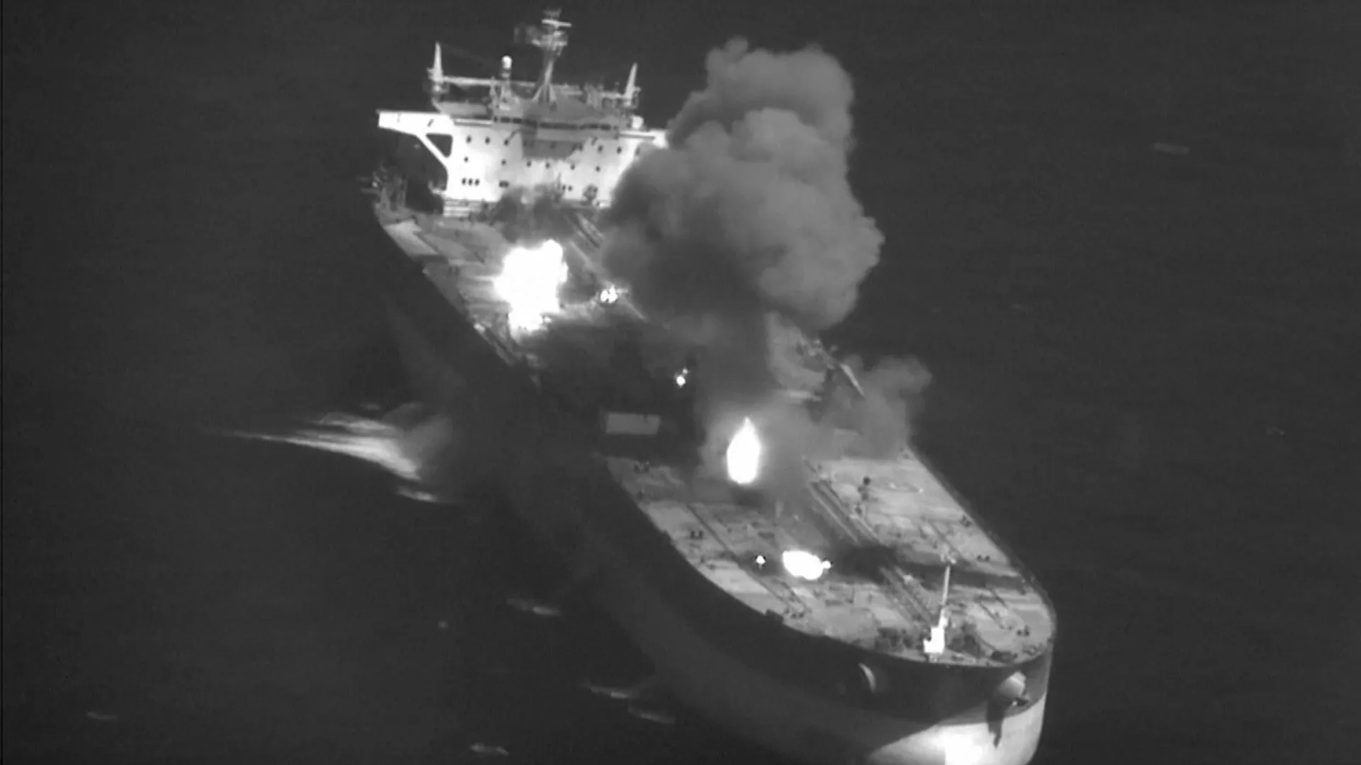 Aerial night image shows a large vessel burning with several fires and thick smoke rising.