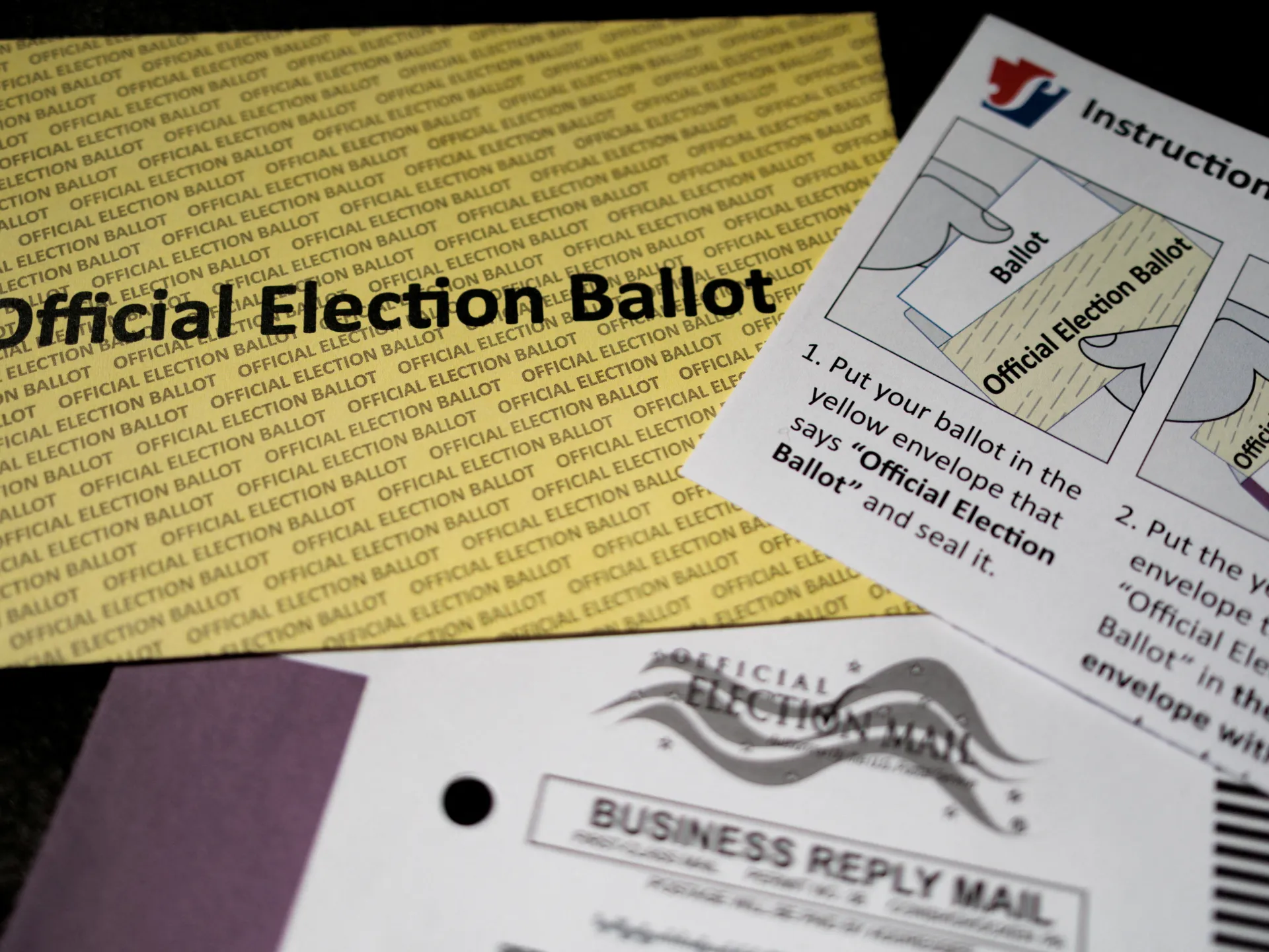 Yellow official election ballot envelope beside illustrated postal voting instructions and a business reply mail form.