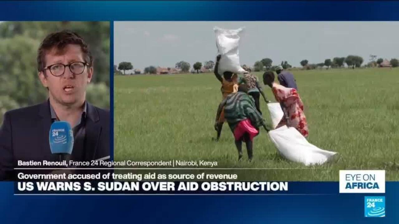 News broadcast shows aid workers carrying large sacks across a green field beside a correspondent.