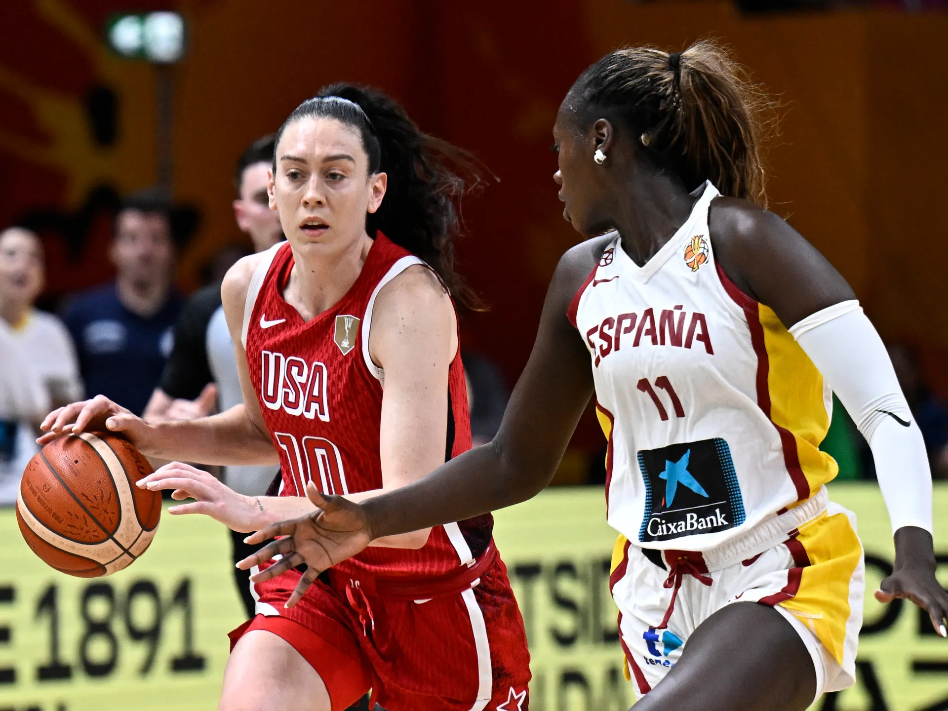 USA and Spain women’s basketball players compete for possession during an international game.