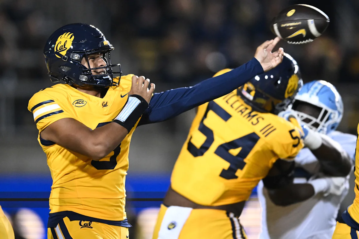 Cal quarterback in gold uniform throws a football during a nighttime college football game.