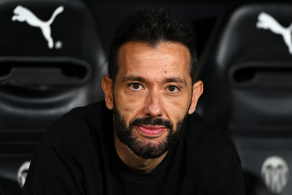 Bearded man in black sportswear seated in front of Puma-branded football seats