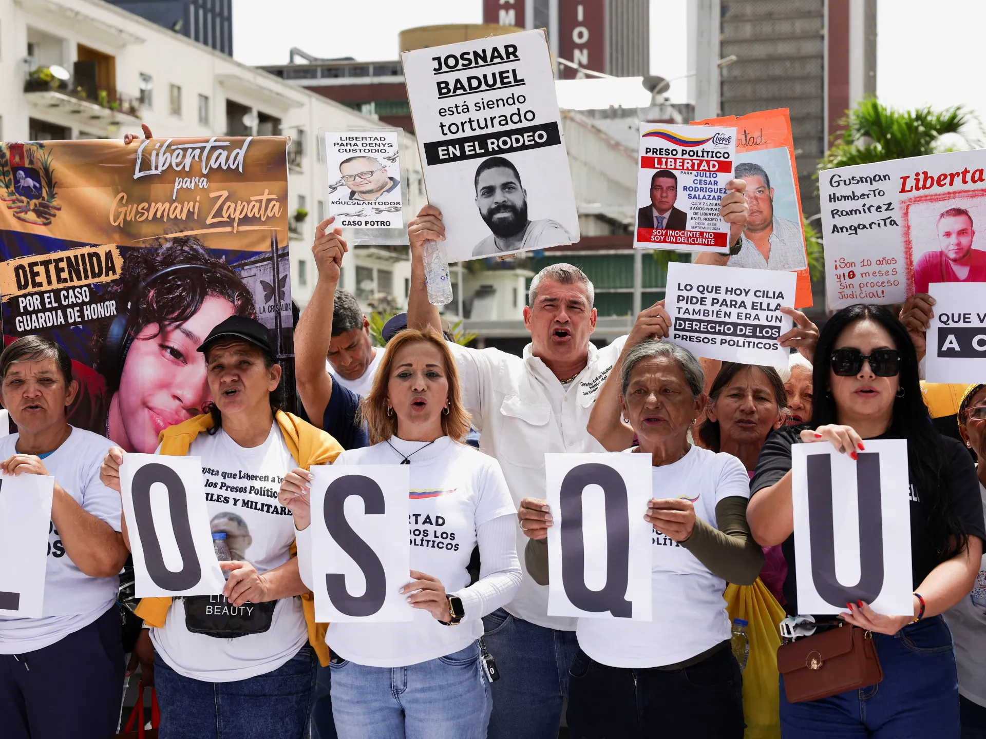 Demonstrators hold signs calling for political prisoners’ release, including large letters spelling “SOSU.”