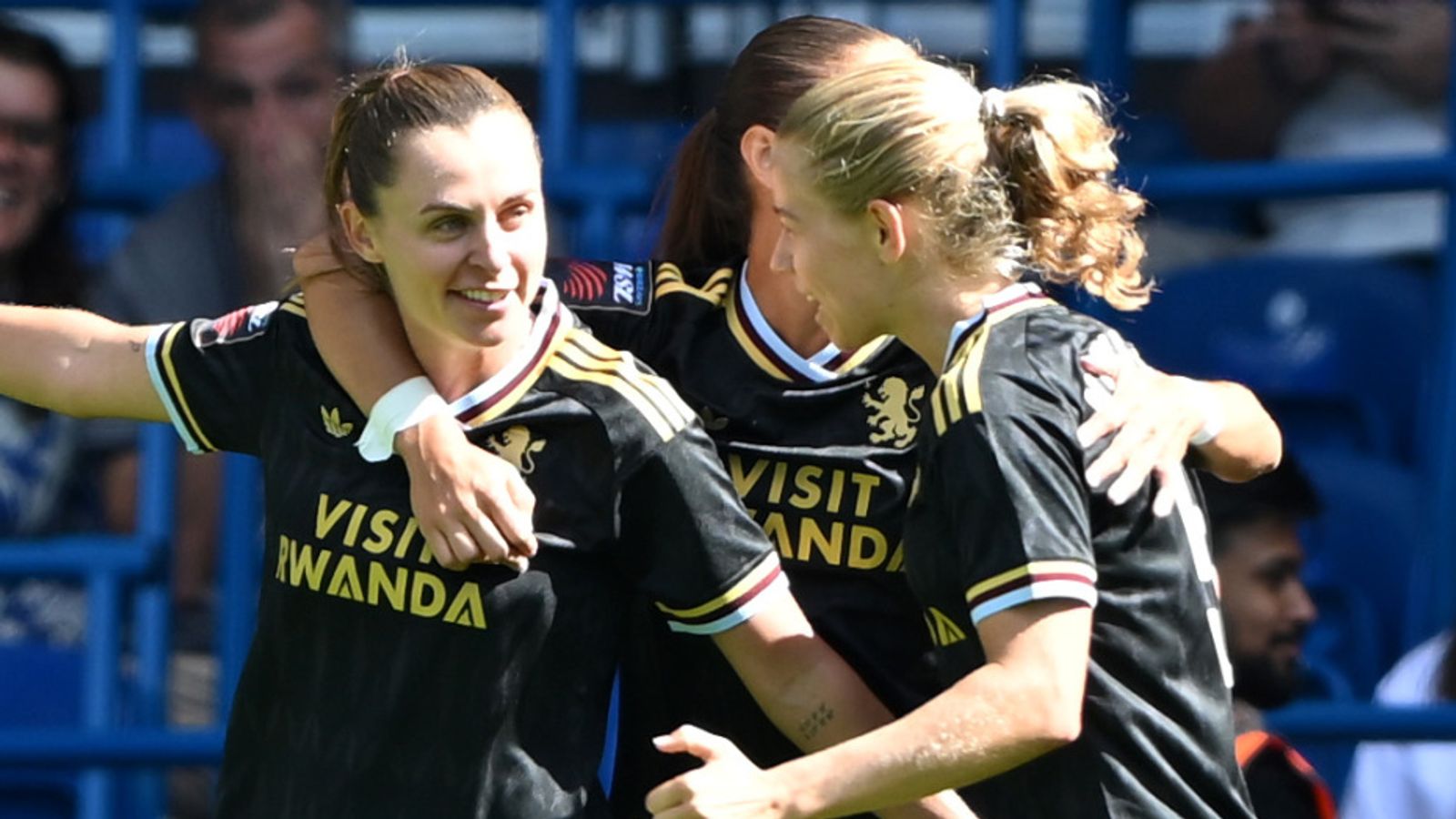 Three footballers in black jerseys embrace during a match celebration.