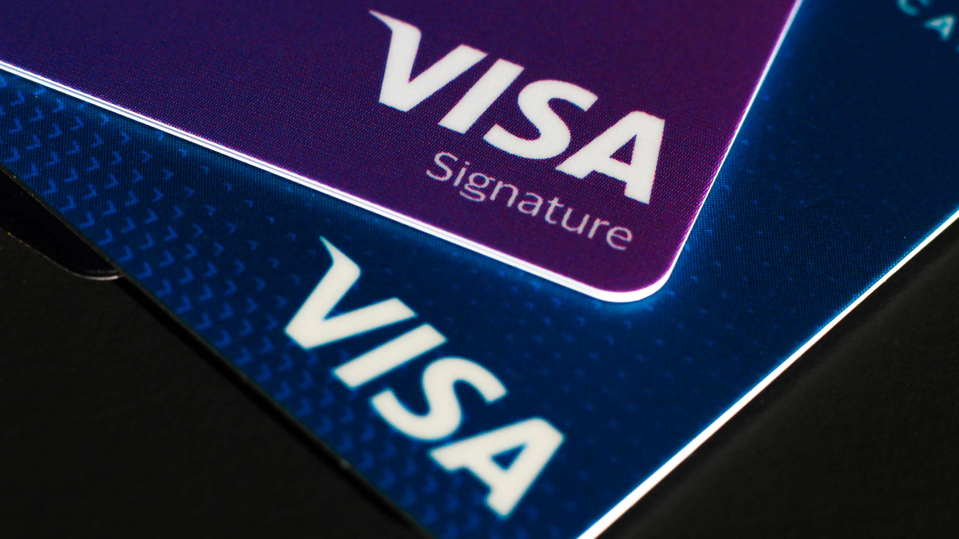 Close-up of overlapping Visa Signature cards displayed at an angle against a dark background.