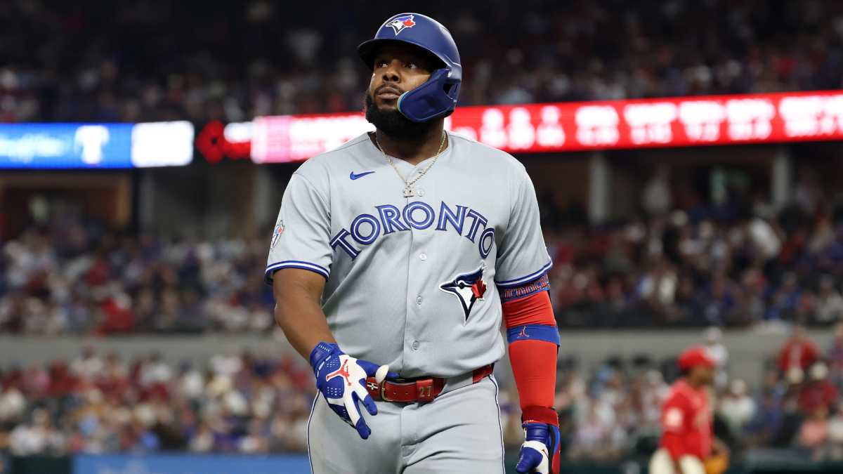 Toronto Blue Jays player in a gray uniform and batting helmet walks on the field during a game.