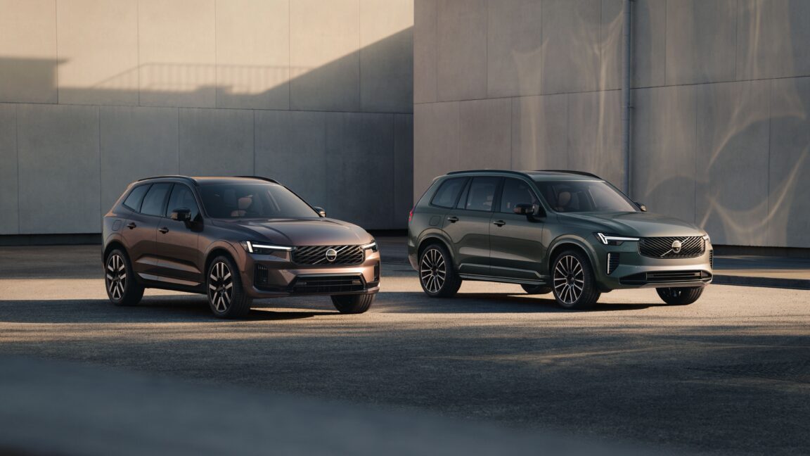 Two Volvo SUVs parked side by side outside a modern building in warm evening light.