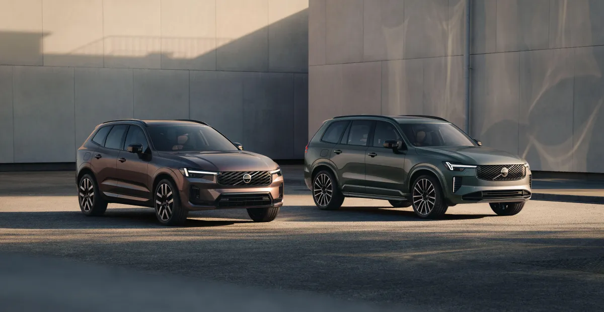 Two Volvo SUVs parked side by side outside a modern building in warm evening light.