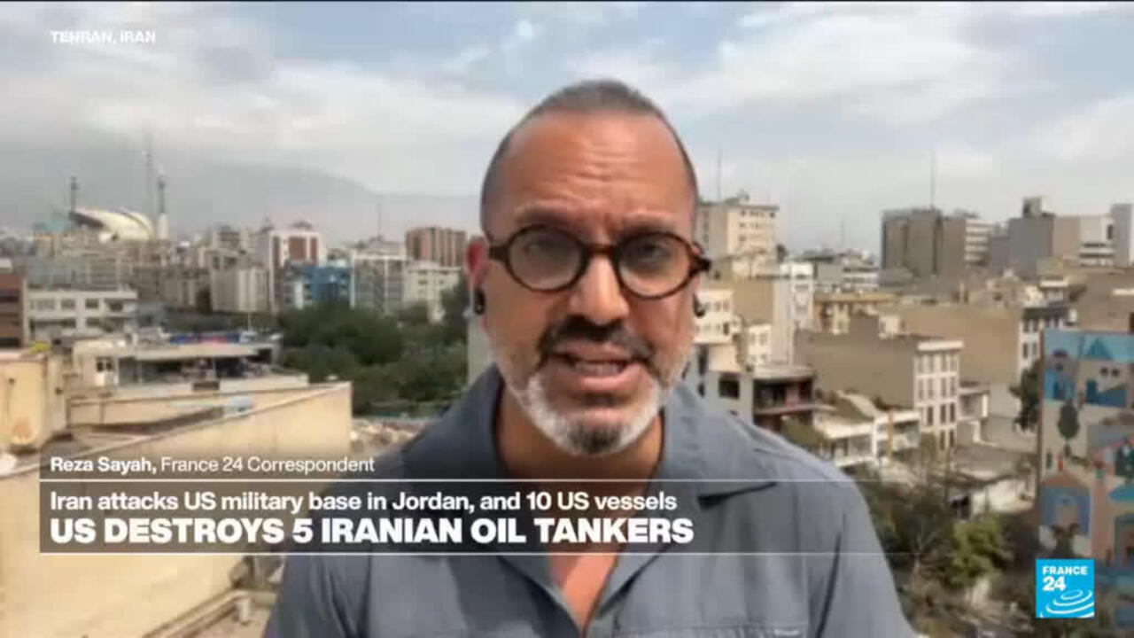 Man wearing glasses speaks to camera with Tehran cityscape and France 24 news graphics behind him