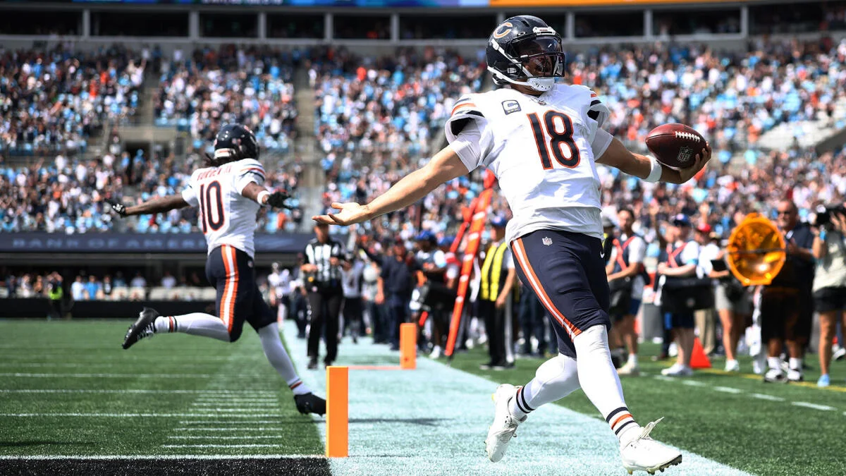 Chicago football player in jersey 18 runs into the end zone holding a football.