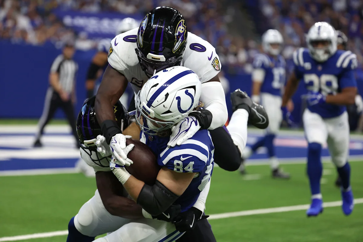 Football player in blue and white uniform tackled by two defenders during a game