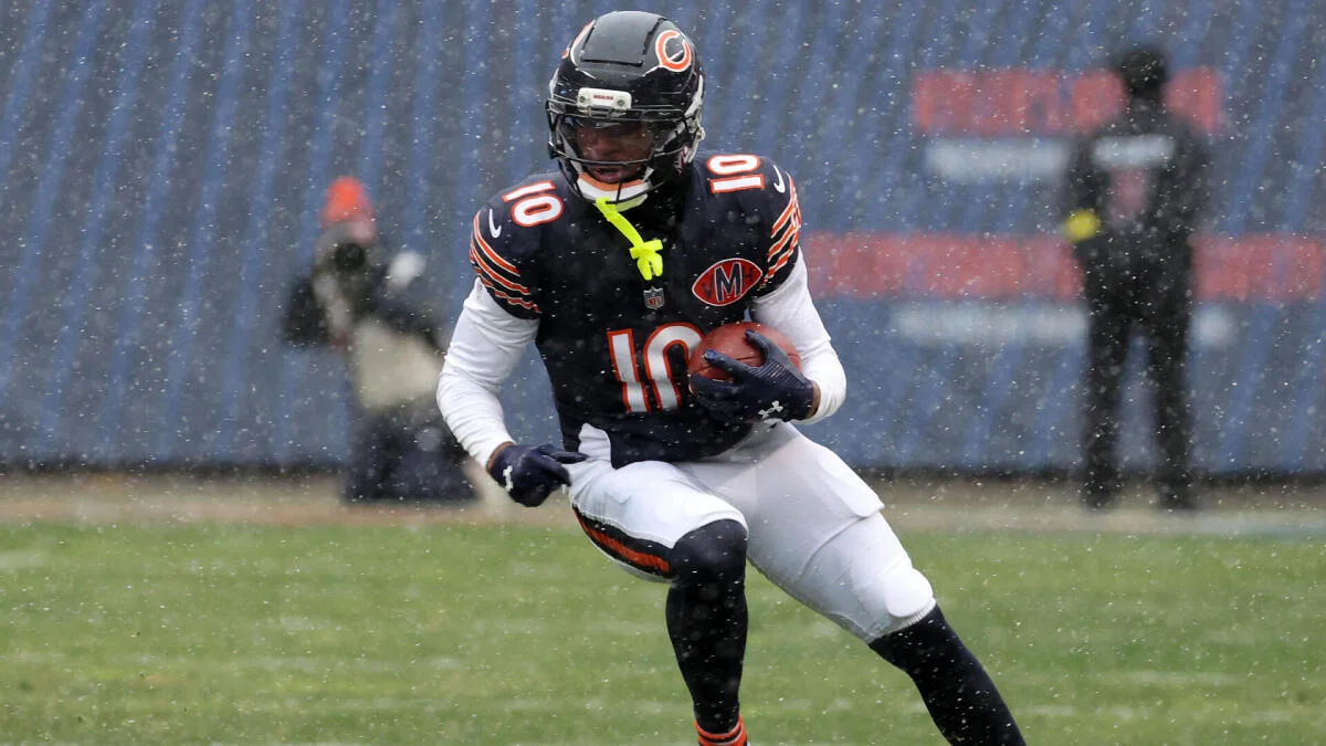 Football player in a Chicago Bears uniform runs with the ball through falling snow.
