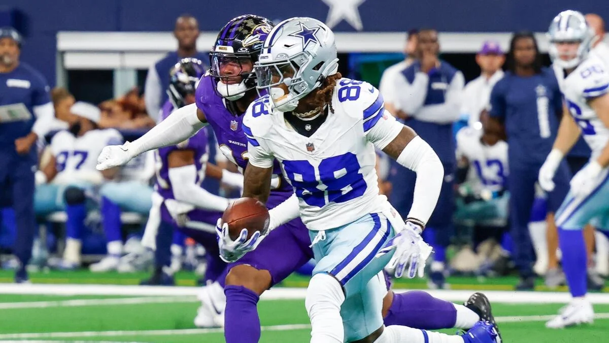 Cowboys receiver carrying the ball as a Ravens defender pursues during an NFL game.