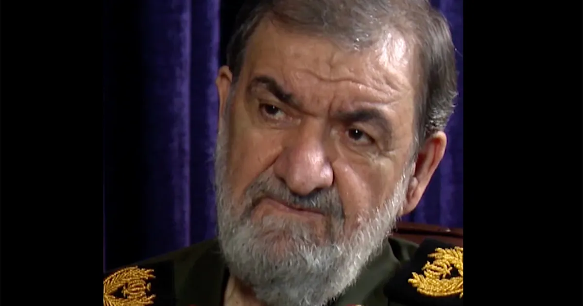 Gray-haired bearded man in a dark military uniform with gold shoulder insignia facing the camera