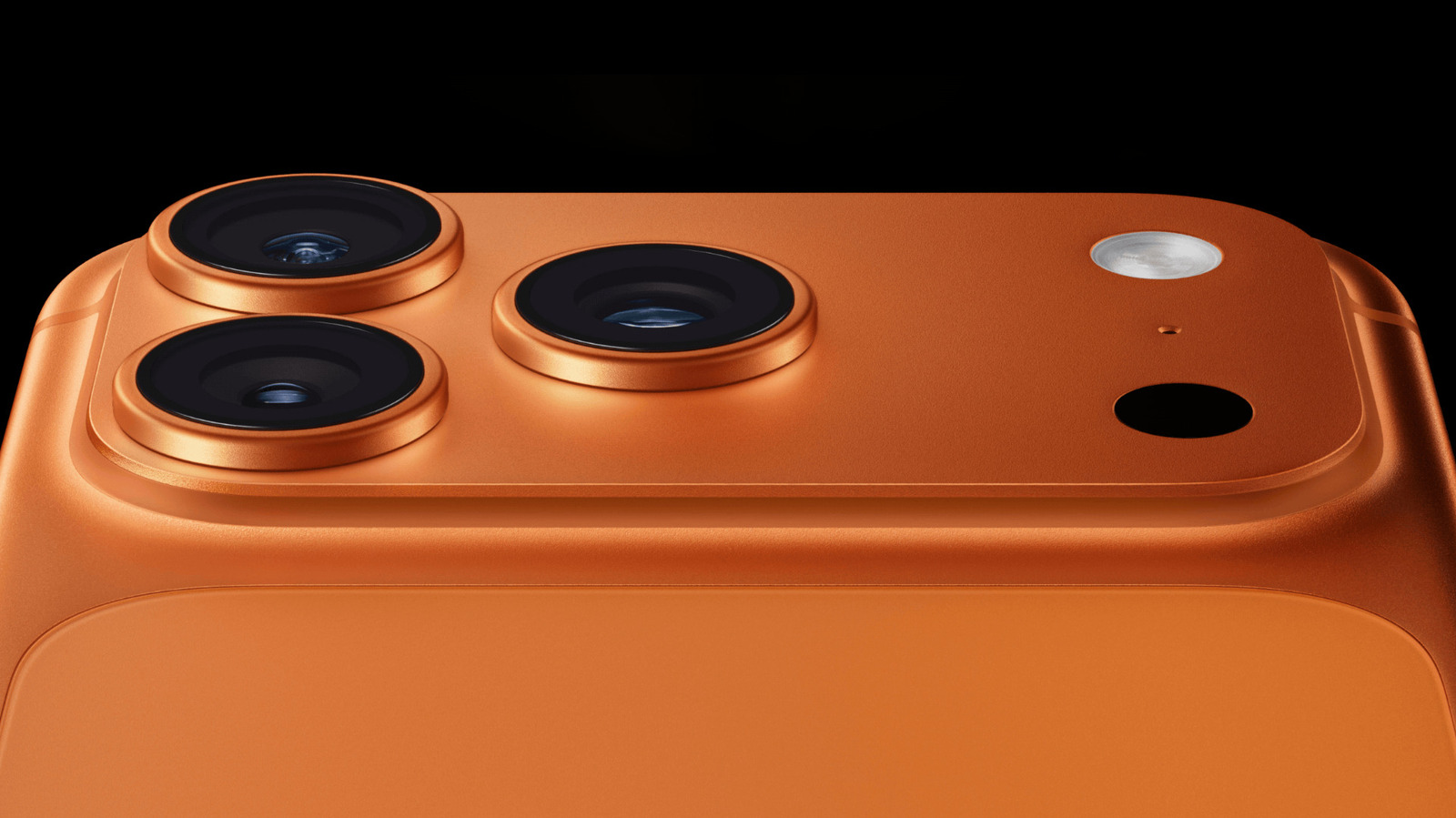 Close-up of an orange iPhone rear camera module with three lenses, flash, and sensor opening.
