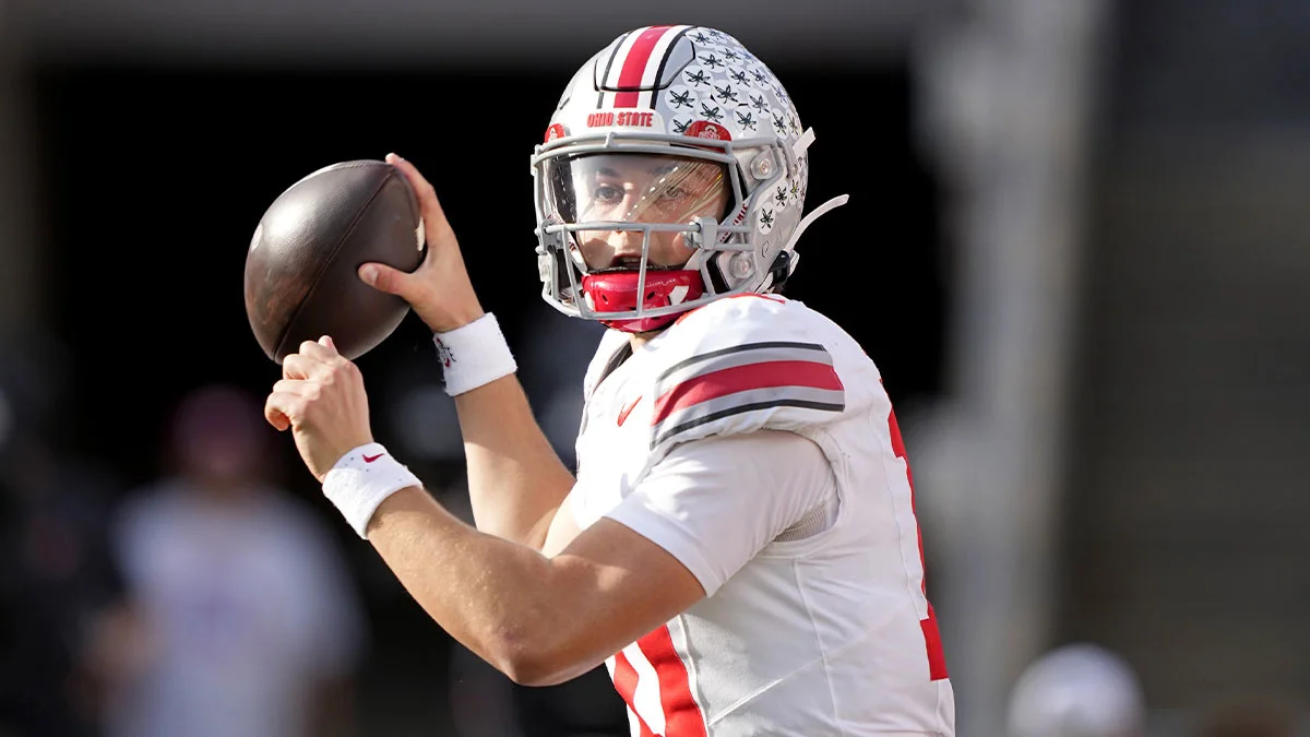 Ohio State football player in helmet holds a football preparing to throw