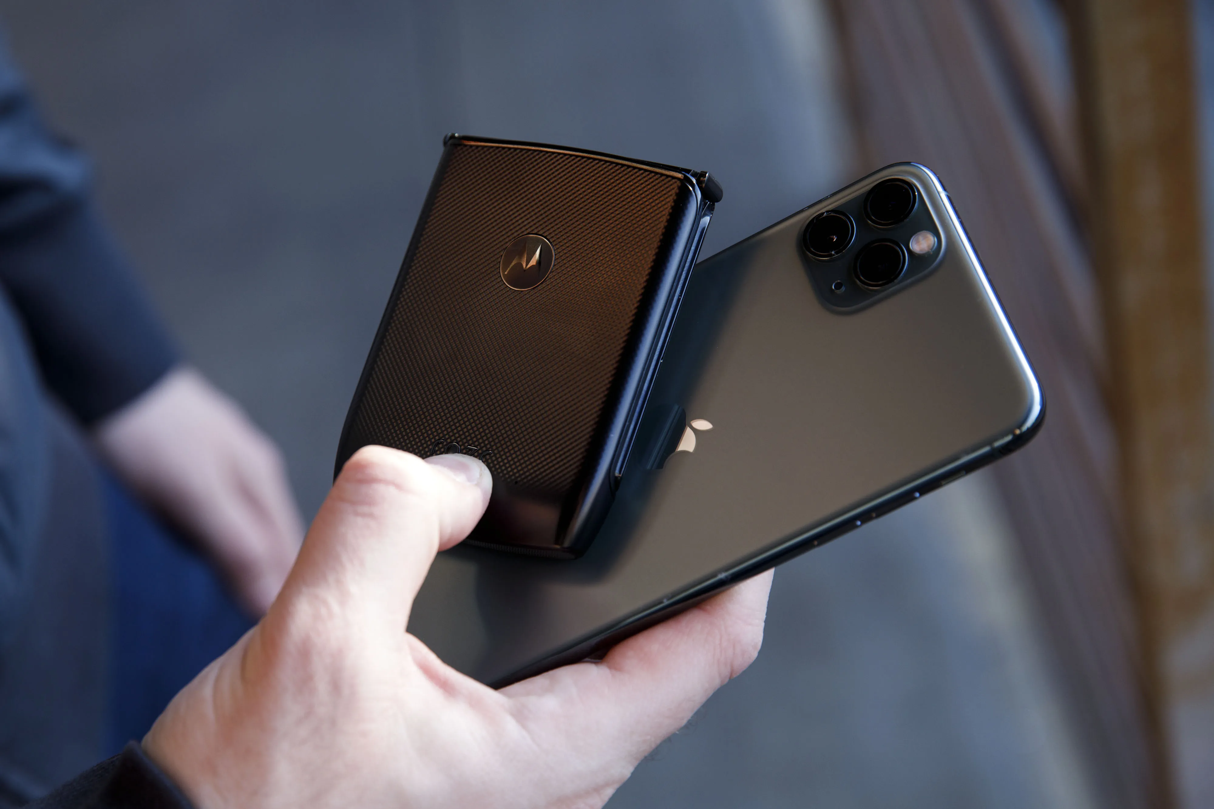 Hand holding an Apple iPhone alongside a Motorola smartphone in close-up