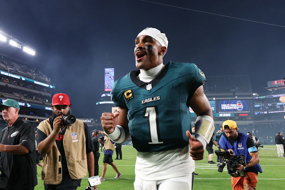 Philadelphia Eagles quarterback wearing number 1 celebrates on the field as cameras surround him