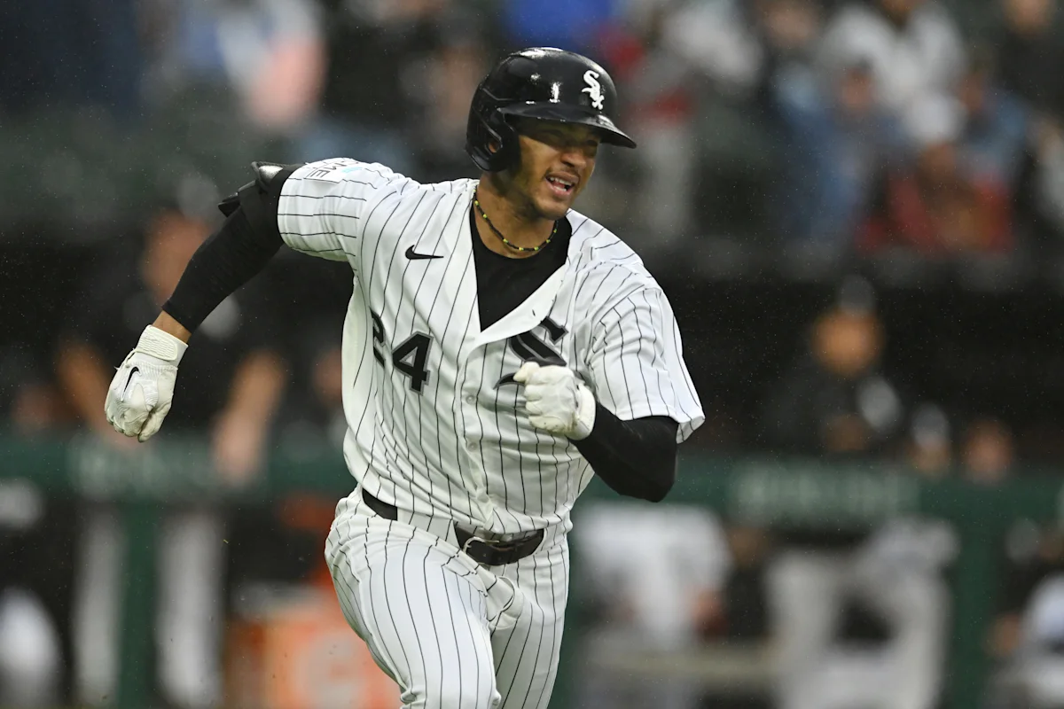 White Sox player in pinstriped uniform runs through falling rain during a baseball game.