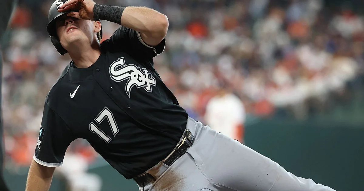 Chicago White Sox player in a black number 17 jersey leans back, raising a hand to his helmet.