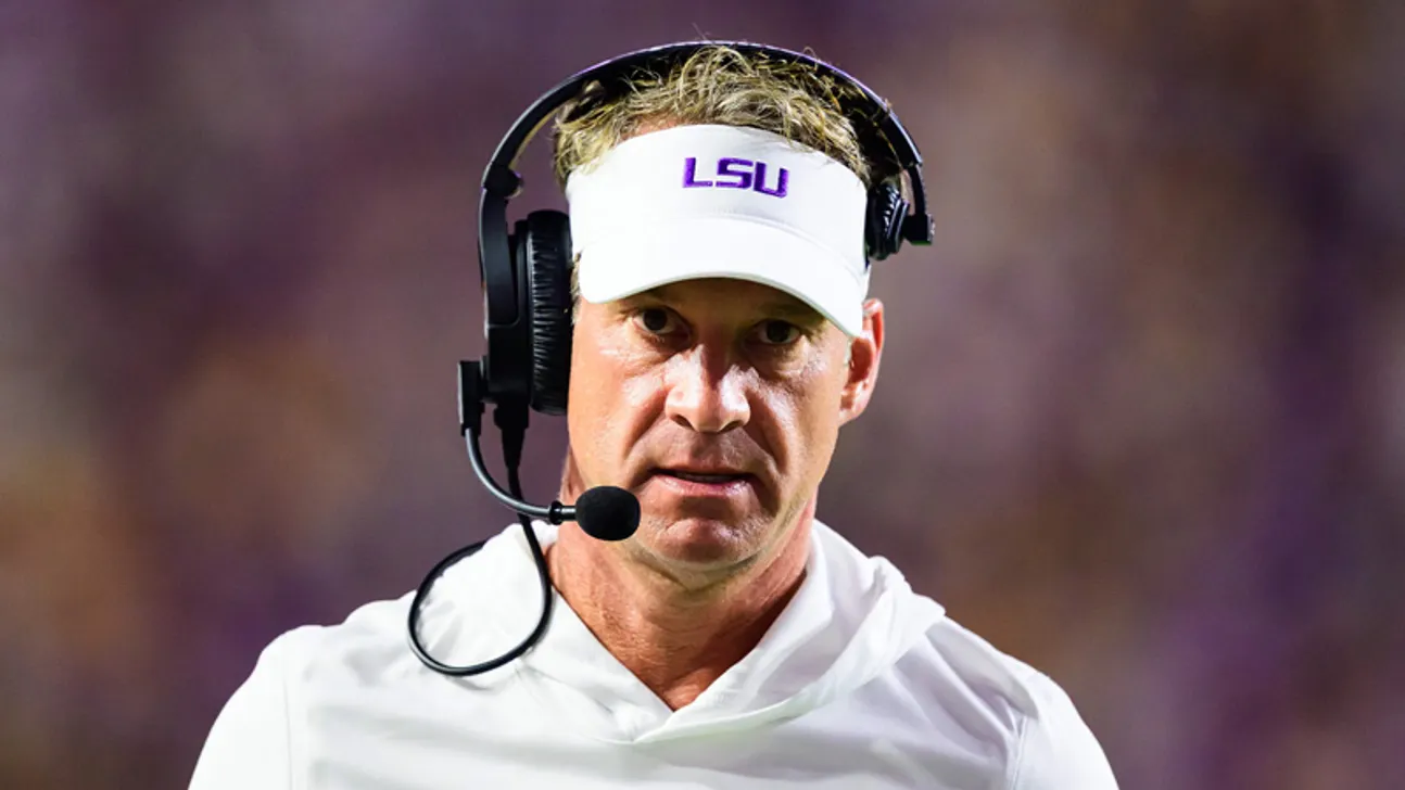 Football coach wearing an LSU visor and headset during a game