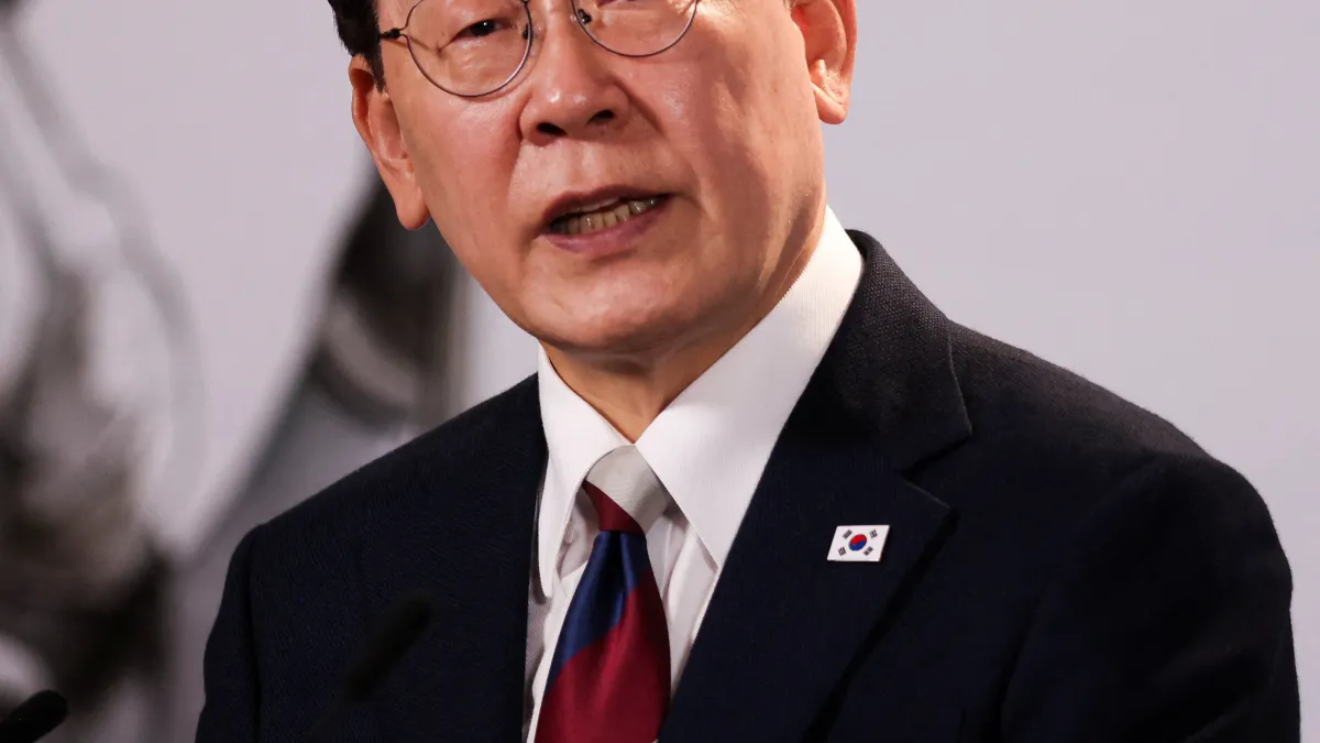 Man in glasses wearing a dark suit, red and blue tie, and South Korean flag lapel pin