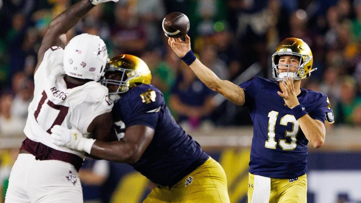 Notre Dame quarterback throws a football as players block during a college football game