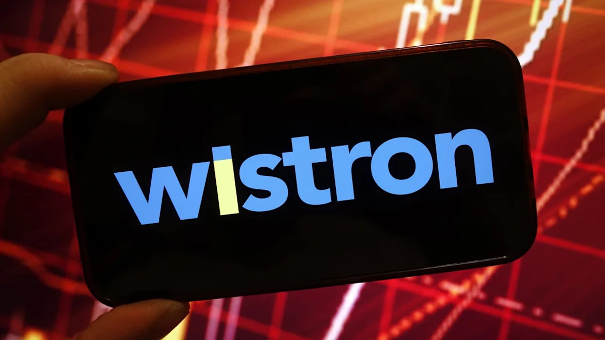 Hand holds a smartphone displaying the Wistron logo against a red financial chart background