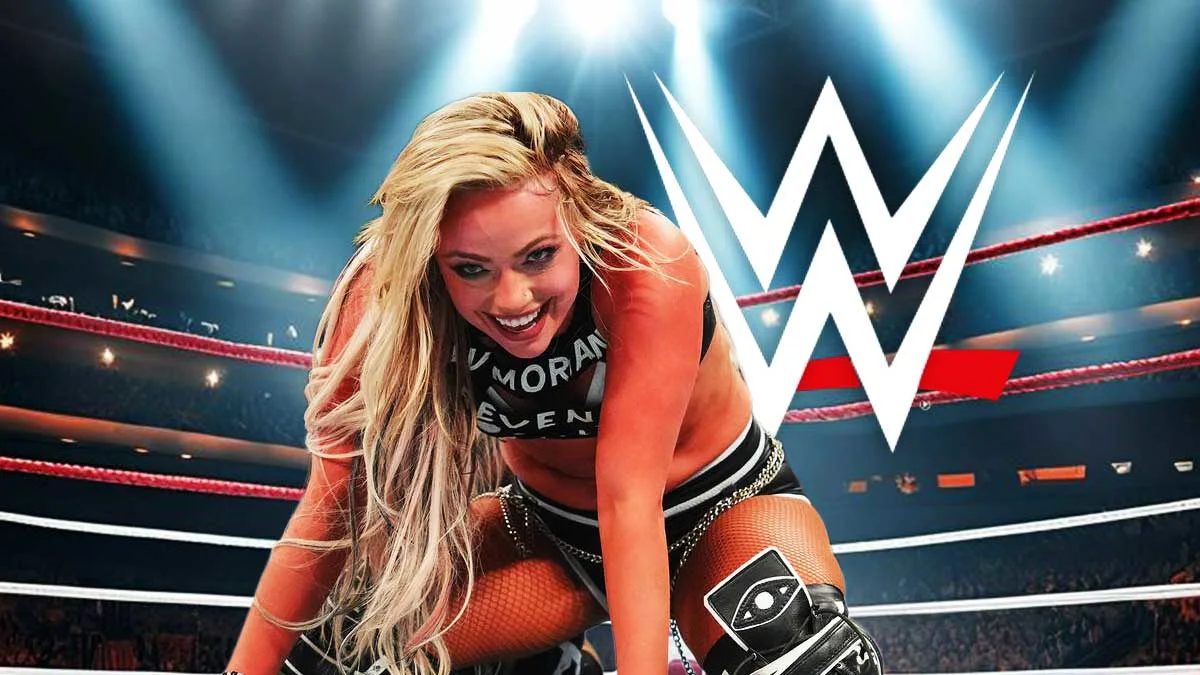 Blonde female wrestler crouches inside a ring beneath bright lights and a large WWE logo.