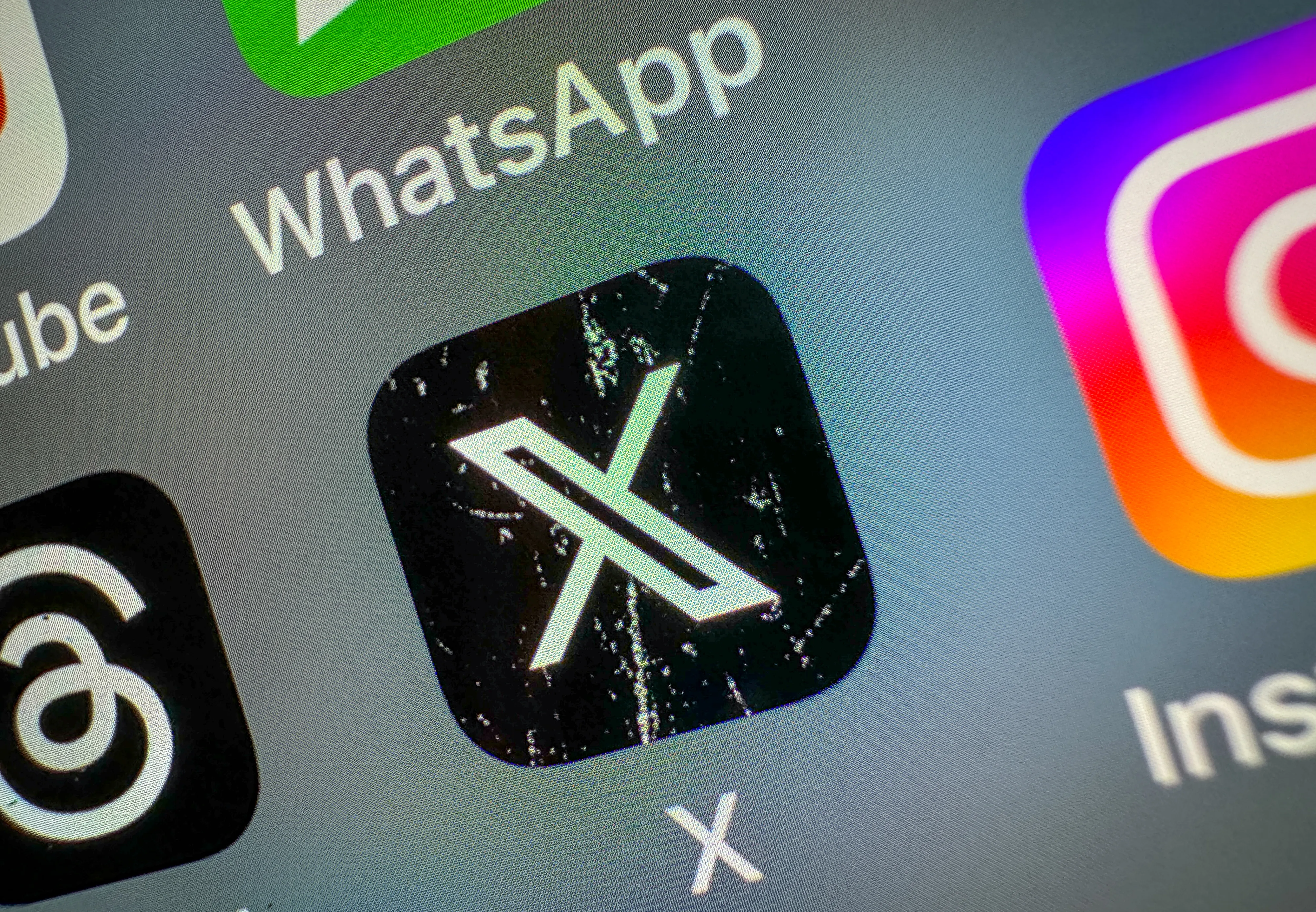 Close-up of a screen displaying the X app icon among other social media application icons.