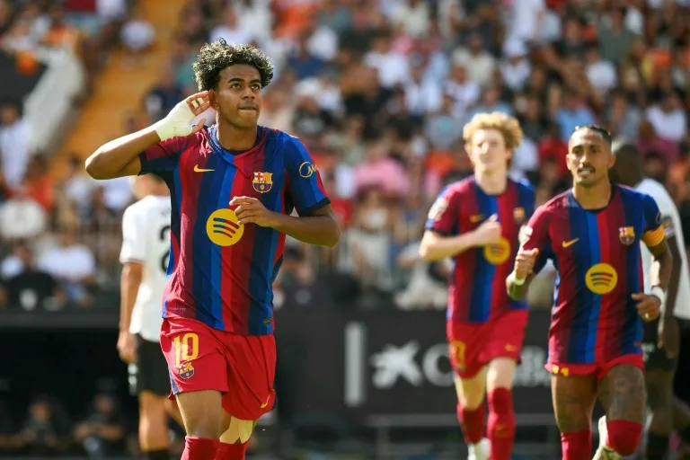 Barcelona players in red and blue kits celebrate during a football match before a packed crowd.